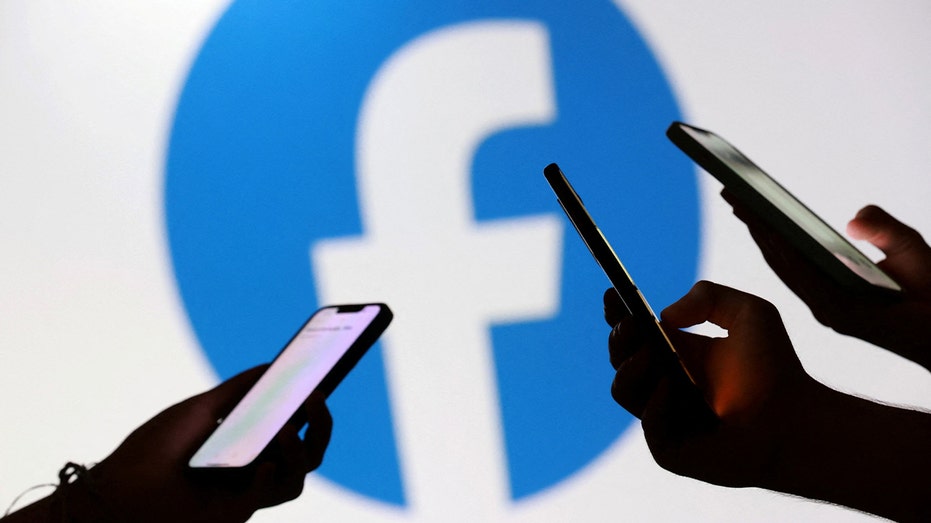 Hands hold the phone in front of Facebook logo