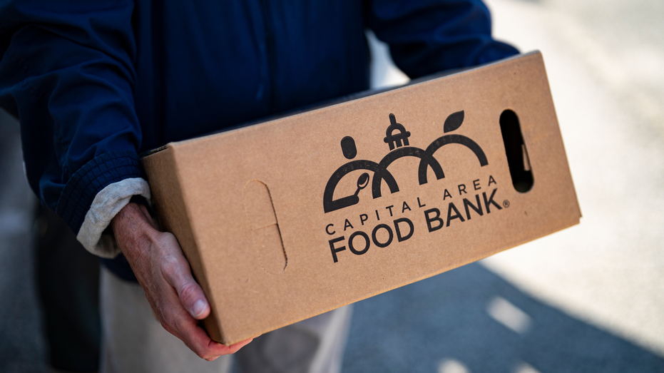 A person loads groceries from a food pantry into a car
