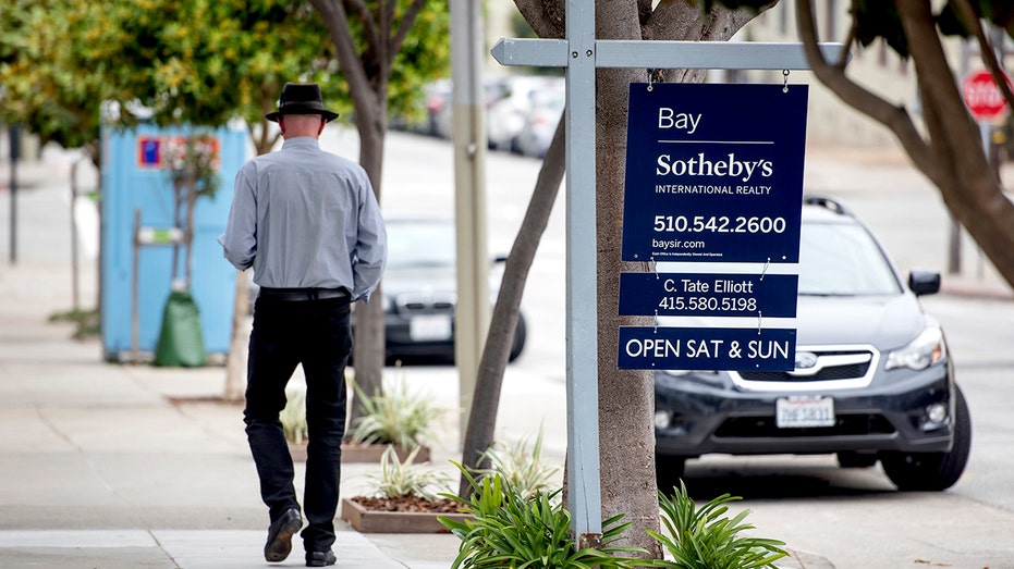 A man is walking through a "Sale" Sign a house in San Francisco, California.