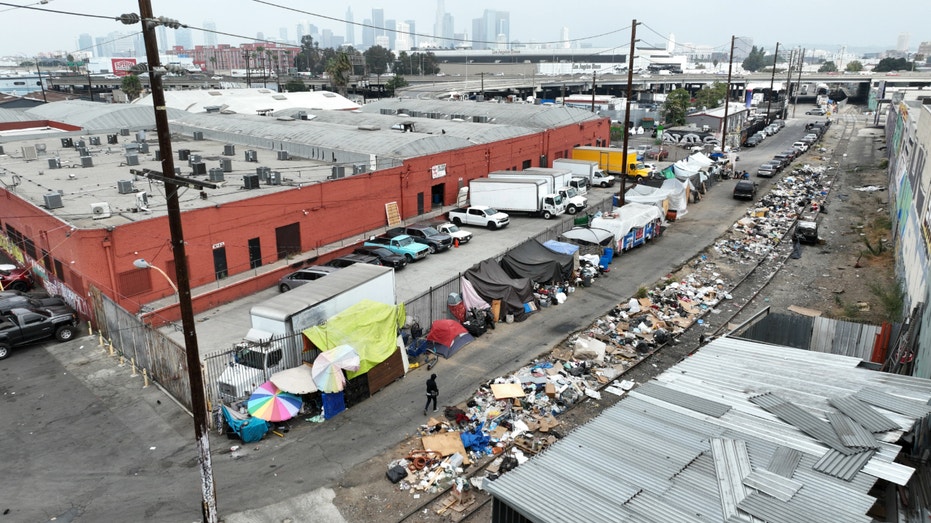 A person walks through trash piles near a homeless encampment in Los Angeles.