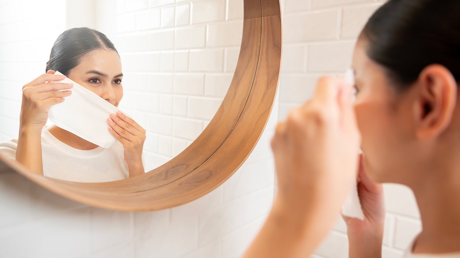 Young woman cleaning removing makeup on her face in bathroom at home , beauty wellness concept
