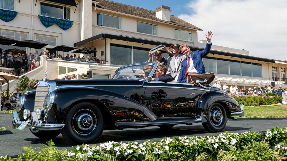 People wave from a A 1953 Mercedes-Benz 300 S Cabriolet.
