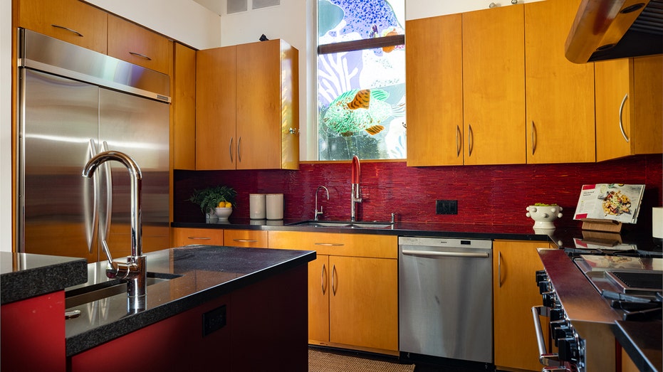 The kitchen includes wooden cupboards and a colored window.