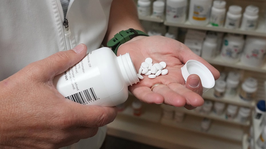 A pharmacist pulls a drug from a shelf inside a pharmacy in Provo, Utah.