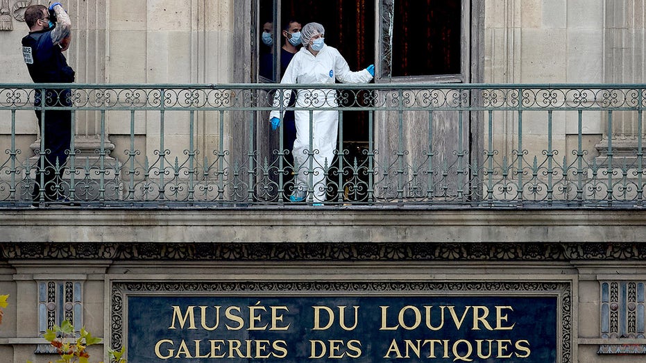 A French Forensics Officer examines the cut window and balcony of a gallery at the Louvre Museum.