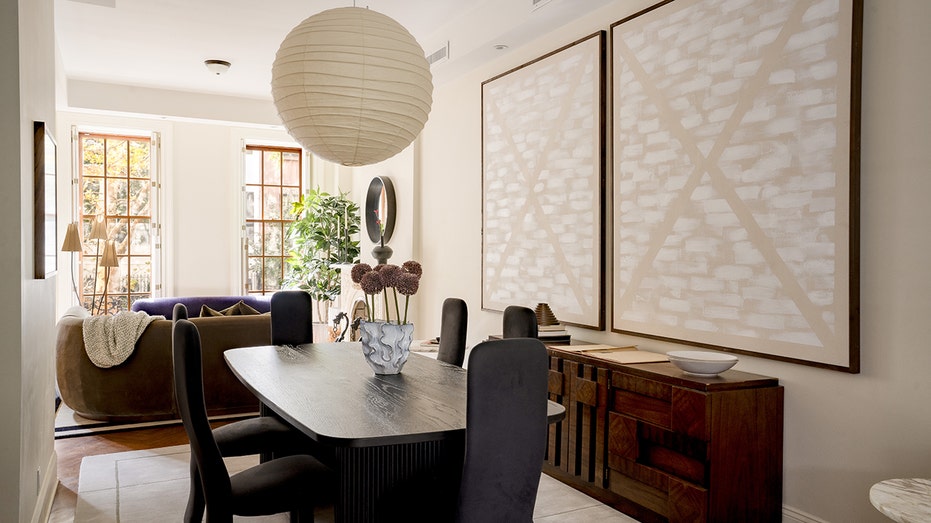 The dining room features paintings on the walls and a unique combination of lighting.