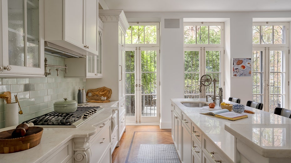 The kitchen features white cabinets and floor-to-ceiling windows.