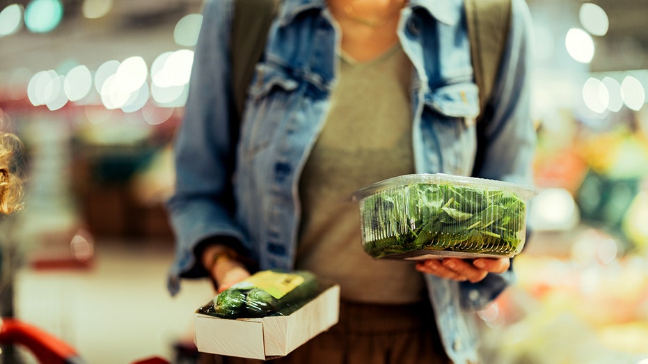 A woman at the supermarket holding spinach.