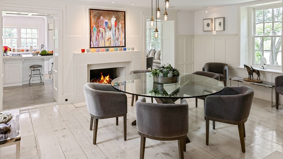 The dining room features a circular table and a wood-burning fireplace.