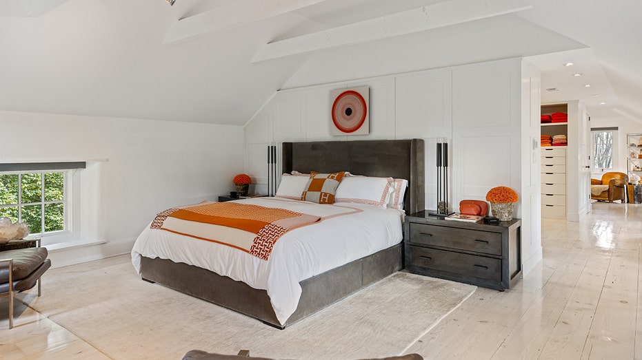 A bedroom with white sheets and colorful pillows.