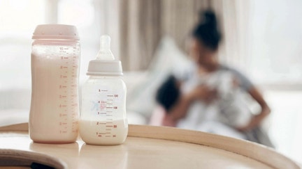 A bottle of baby formula with a mother holding her baby. - Fox Business News