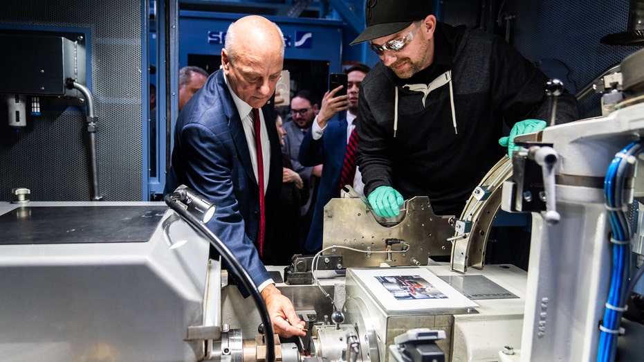 U.S. Treasurer Brandon Beach and a U.S. mint worker hold one of the last pennies