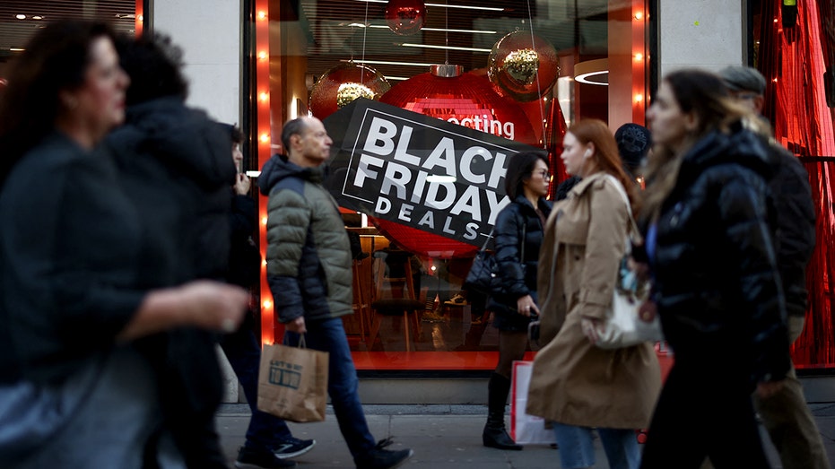 Shoppers pass window displays advertising Black Friday.