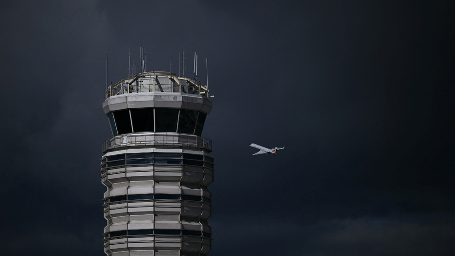 An airplane is seen flying behind a control tower at Reagan National Airport
