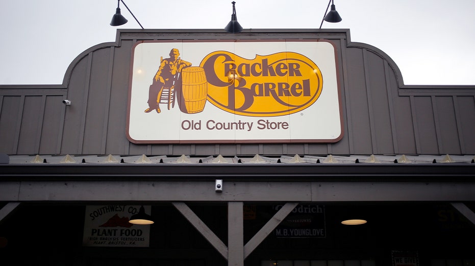 Exterior sign of a Cracker Barrel restaurant and gift shop against a clear sky.
