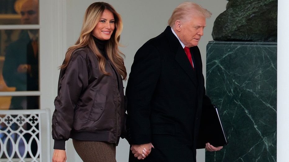 First Lady Melania Trump smiles while holding hands with President Donald Trump