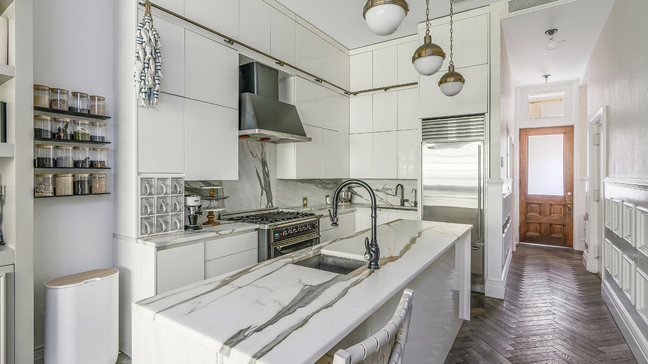 The kitchen features a large center island with a second sink, as well as a spice rack on the wall.