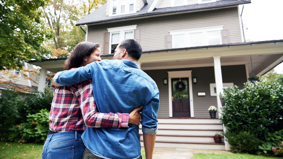 A couple in front of a home.