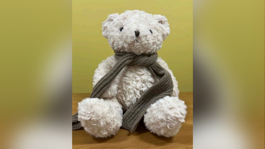 white teddy bear with gray scarf tied around neck