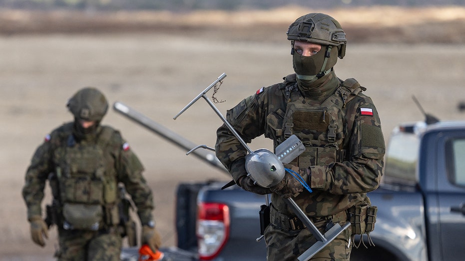 A Polish soldier carries an interception drone of the American MEROPS counter drone system during tests at the Nowa Deba military training ground, south-eastern Poland.