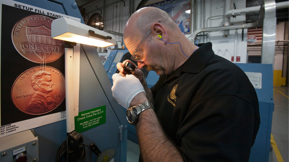 A worker inspects finished penny coins at the United States Mint in Denver.