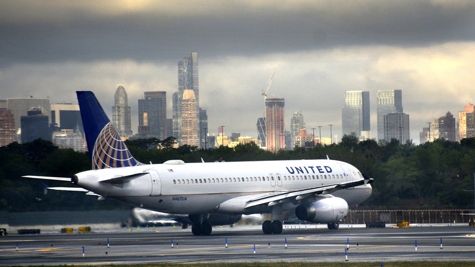 united airlines plane on tarmac during cloudy day with city background seen