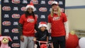 Josh Metellus and Andrew Van Ginkel poses with child at Raising Cane's bike giveaway. - Fox News