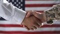 FILE PHOTO: A soldier and businessman are pictured shaking hands. - Fox News