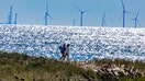 Madaket beachgoers walk along the beach in this 800mm telephoto view that compresses distance of the Vineyard Wind turbines 15 miles away.  - Fox Business News