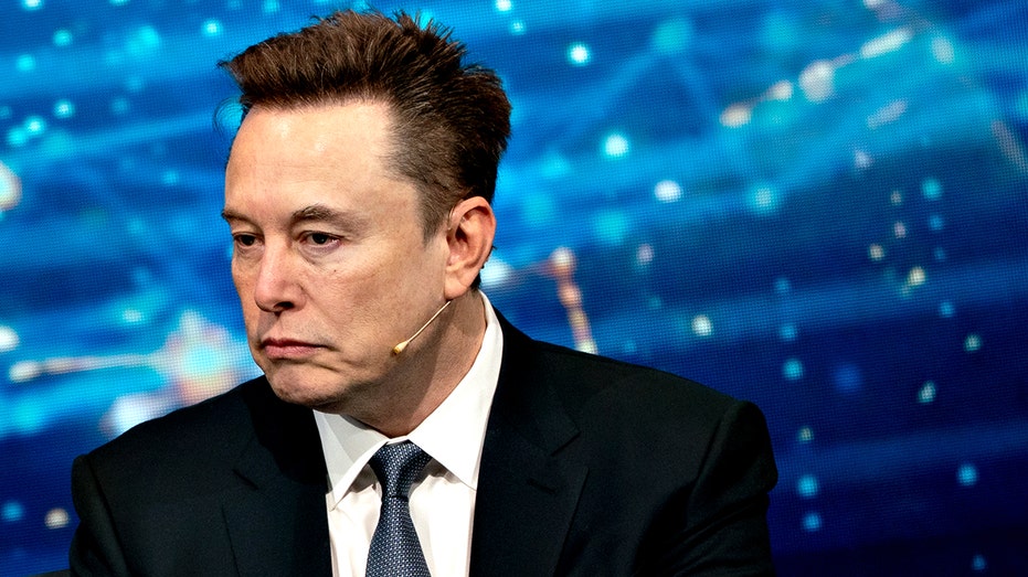 Elon Musk in dark suit listening