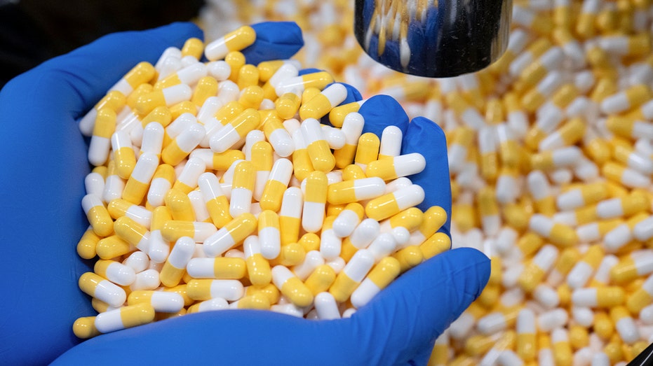 Hands holding a pile of pills