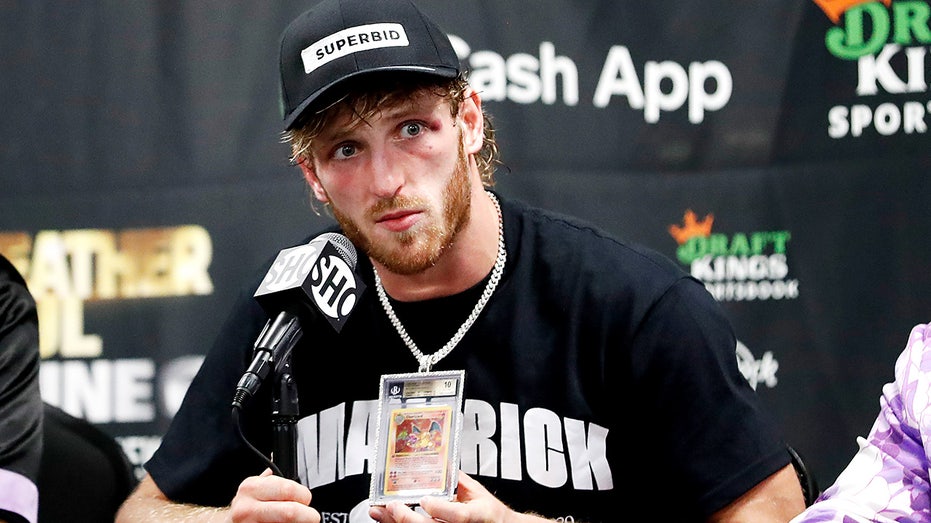 Logan Paul speaks at a press conference while wearing a chain featuring a Charizard Pokémon card.