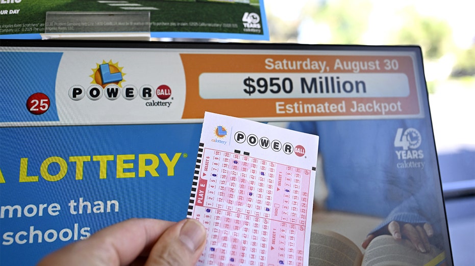 A Powerball ticket rests near a screen displaying jackpot information at a California store.