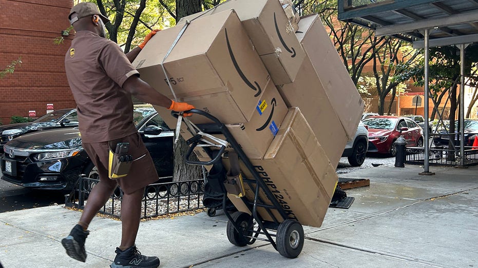 UPS delivery person with loaded hand truck on sidewalk in Manhattan.