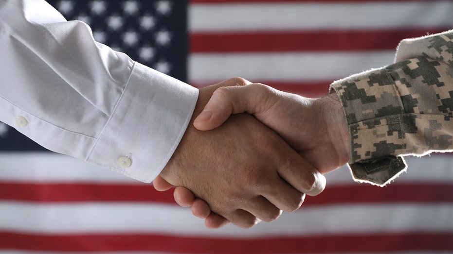 Soldier and businessman shaking hands against flag of USA, closeup