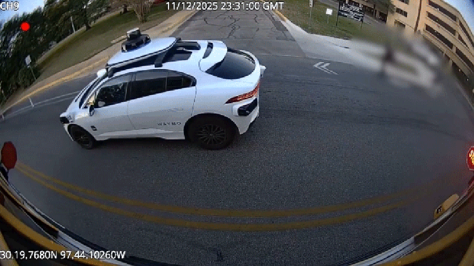 white waymo car passes school bus stop signs