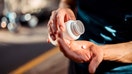 Close up of human hands. Man holding the medicine bottle in one hand and pill in other - Fox Business News
