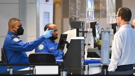 TSA agents check passenger identity documents at a security checkpoint security at Reagan National Airport on the first day of the US government shut down in Arlington, Va., on Oct.1, 2025 - Fox Business News