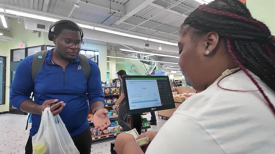 A cashier hands money to a buyer in the grocery store