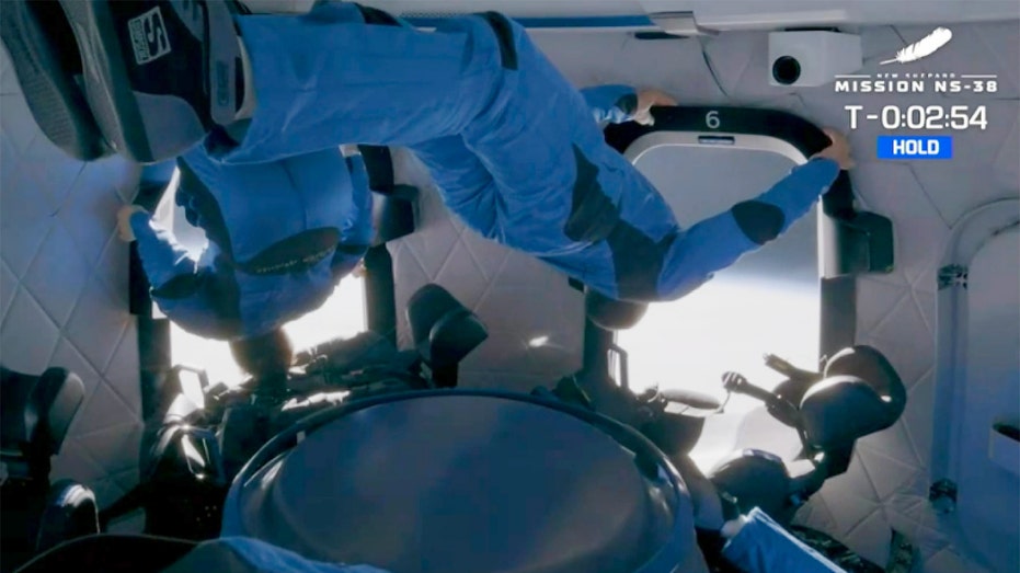 People floating in a spacecraft in blue suits.