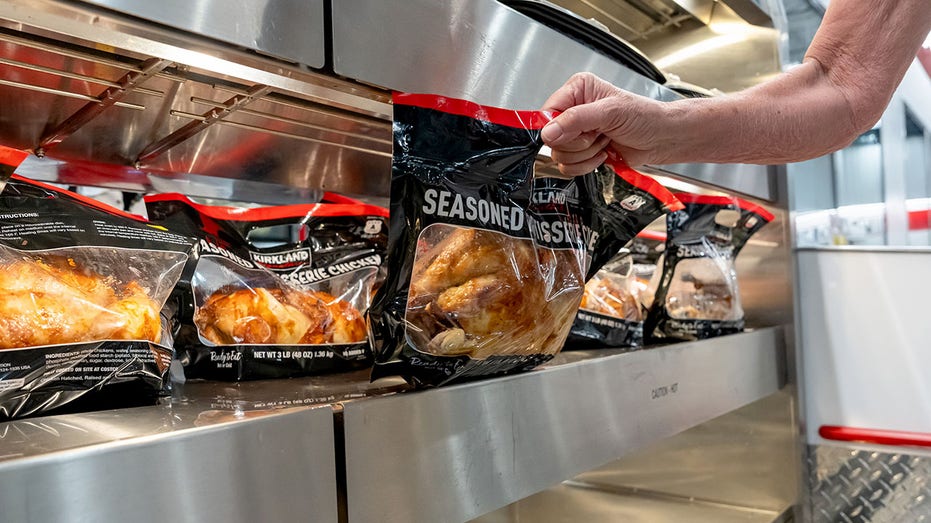 A shopper picks up a rotisserie chicken