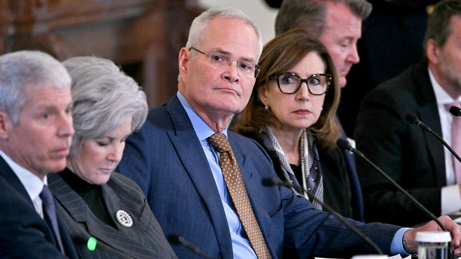 Senior U.S. officials and an oil CEO sit side-by-side at a long table inside the East Room of the White House.
