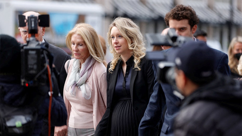 A former technology executive walks toward a courthouse surrounded by relatives ahead of a major legal decision.