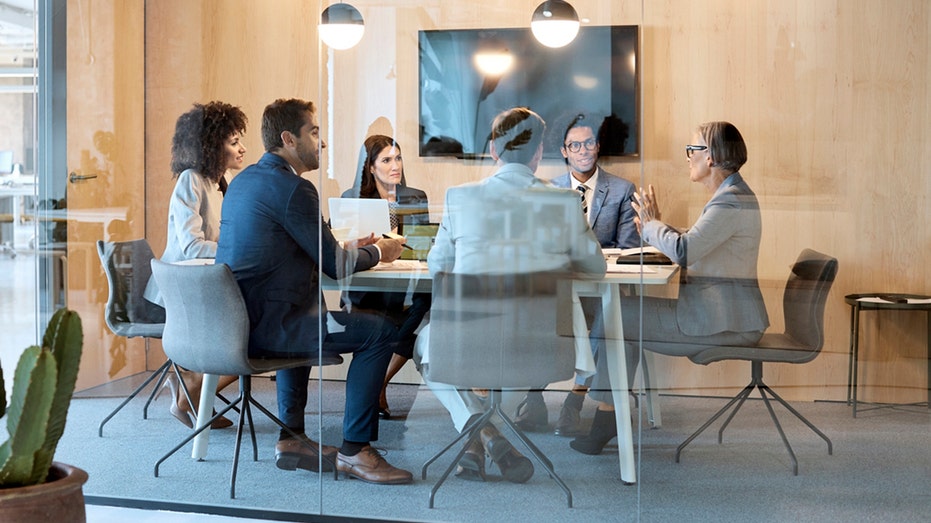 Employees sit at a table during a corporate meeting.