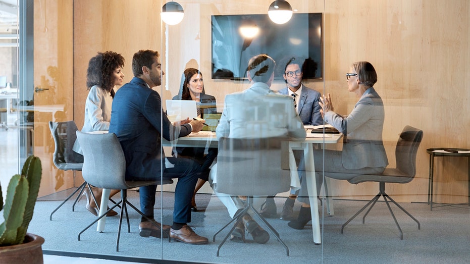 Employees sit at a table during a corporate meeting.