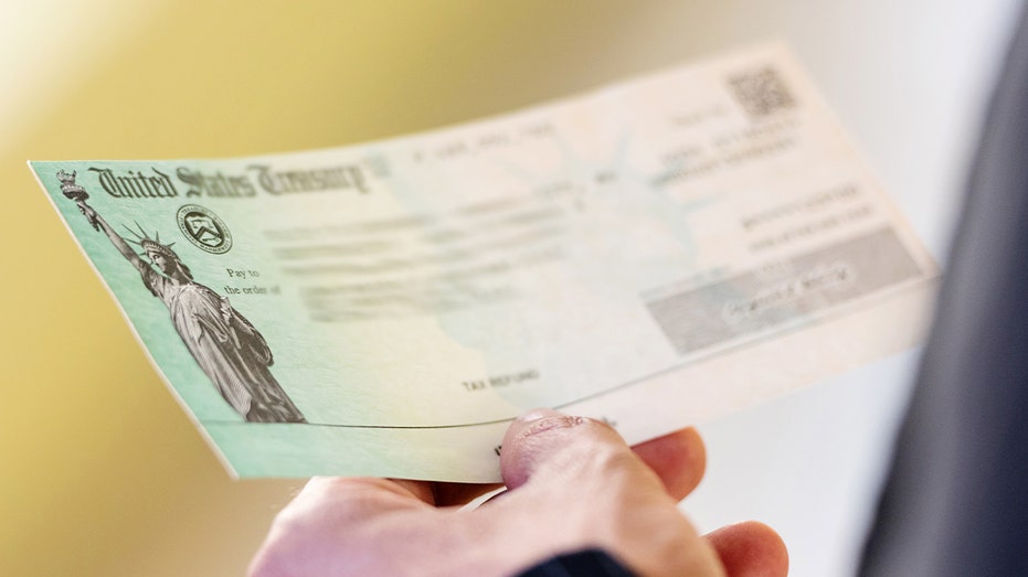 A man's hands holding a U.S. Treasury check.