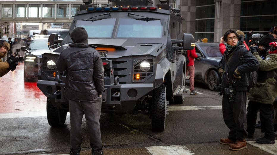 A person stands in front of a SWAT vehicle in Minneapolis.