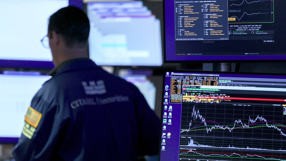 A stock trader monitors multiple screens on the busy trading floor as markets react to breaking news.