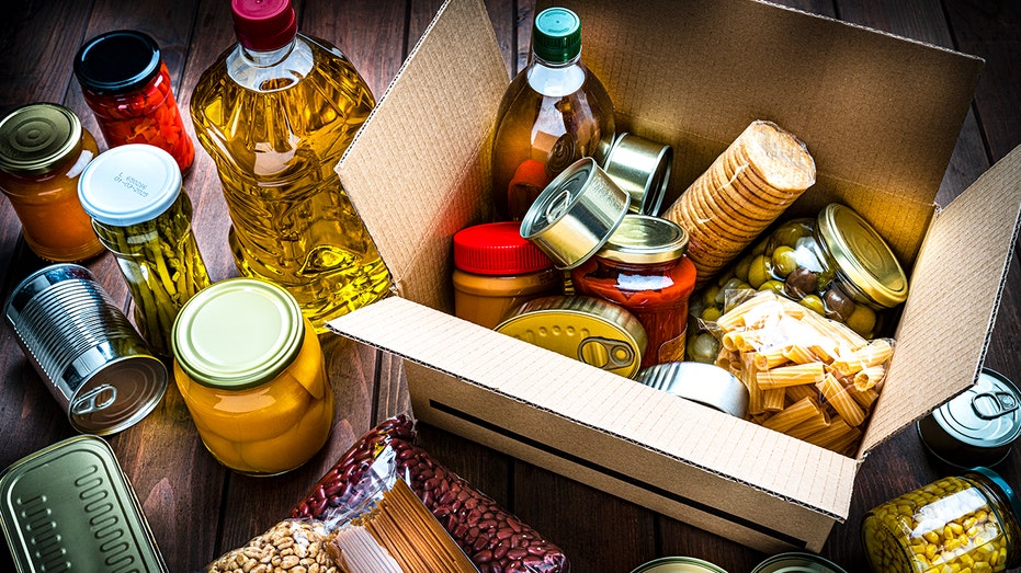 Cardboard box filled with non-perishable foods on wooden table