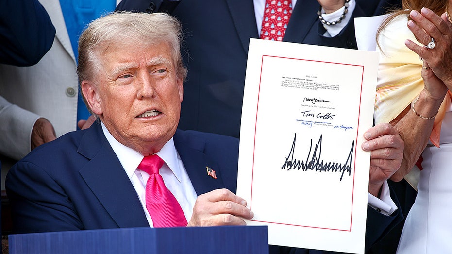 Donald Trump signs a document at a table while surrounded by Republican lawmakers during an outdoor event.